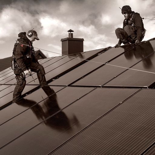 Två män installerar solceller på tak